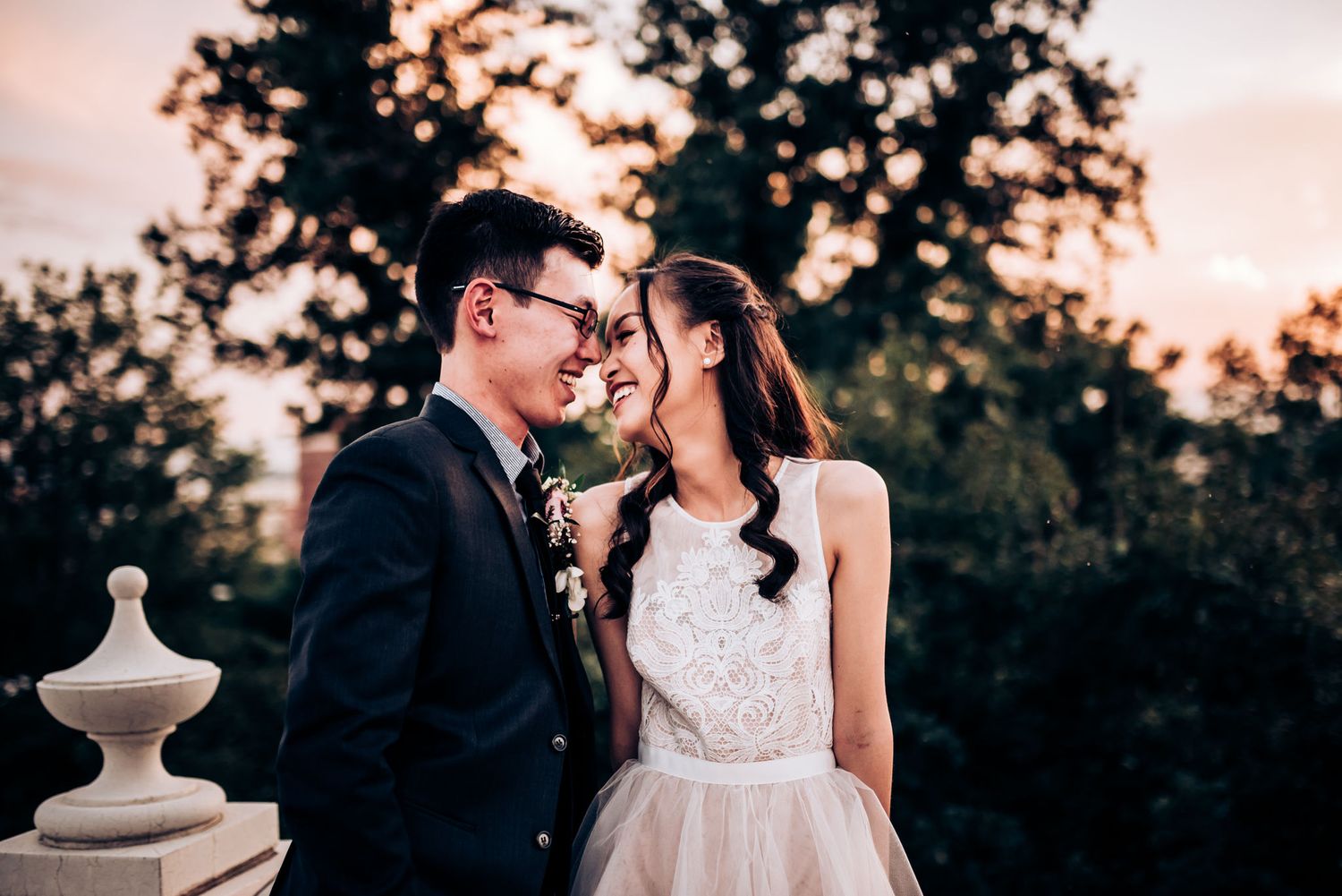 Intimate wedding portrait against sunset sky with romantic lighting.