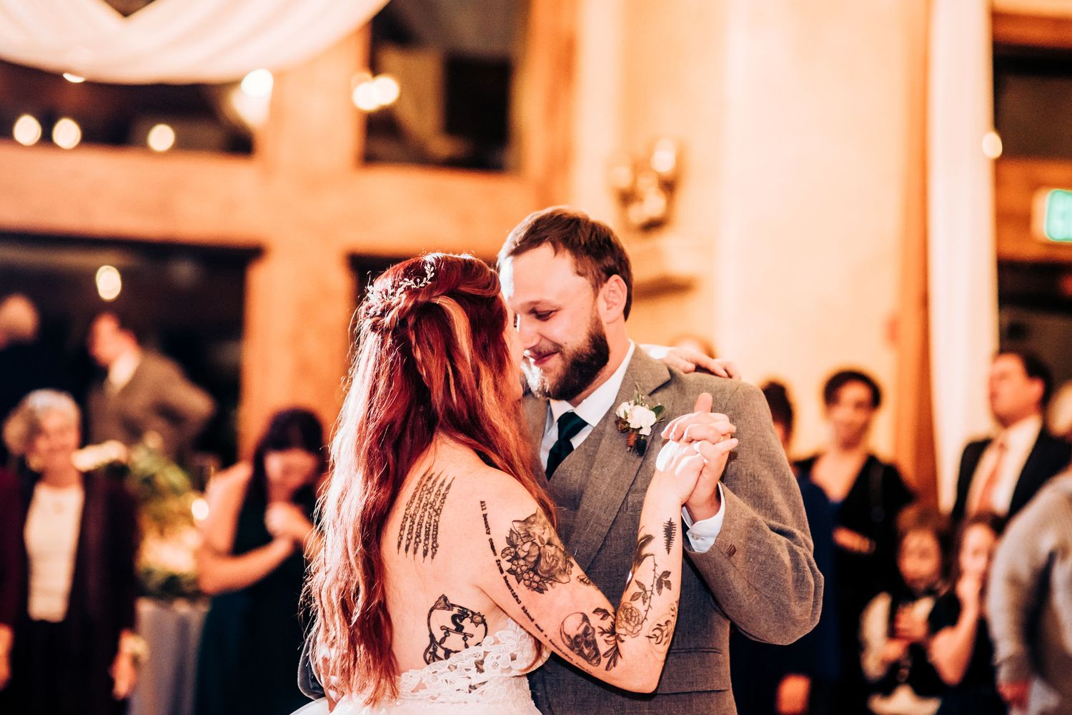Couple shares romantic first dance at wedding reception under warm lighting.