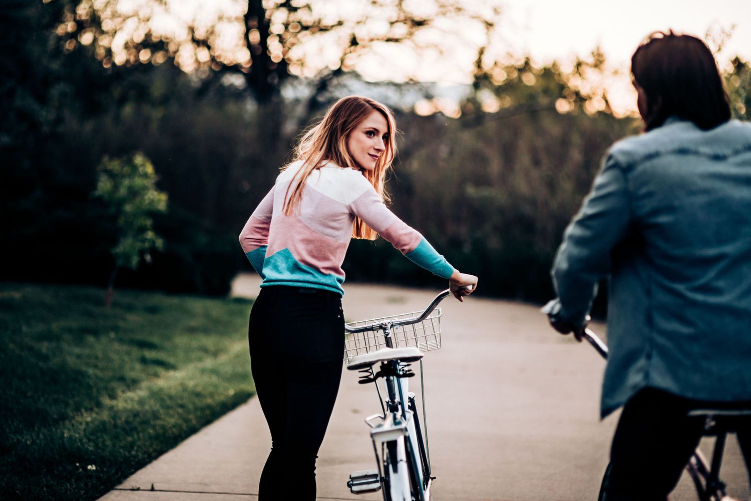 Two people pause during their bike ride to share a playful moment at sunset.