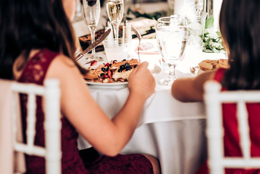 Wedding dinner table setting with wine glasses and burgundy decor details.