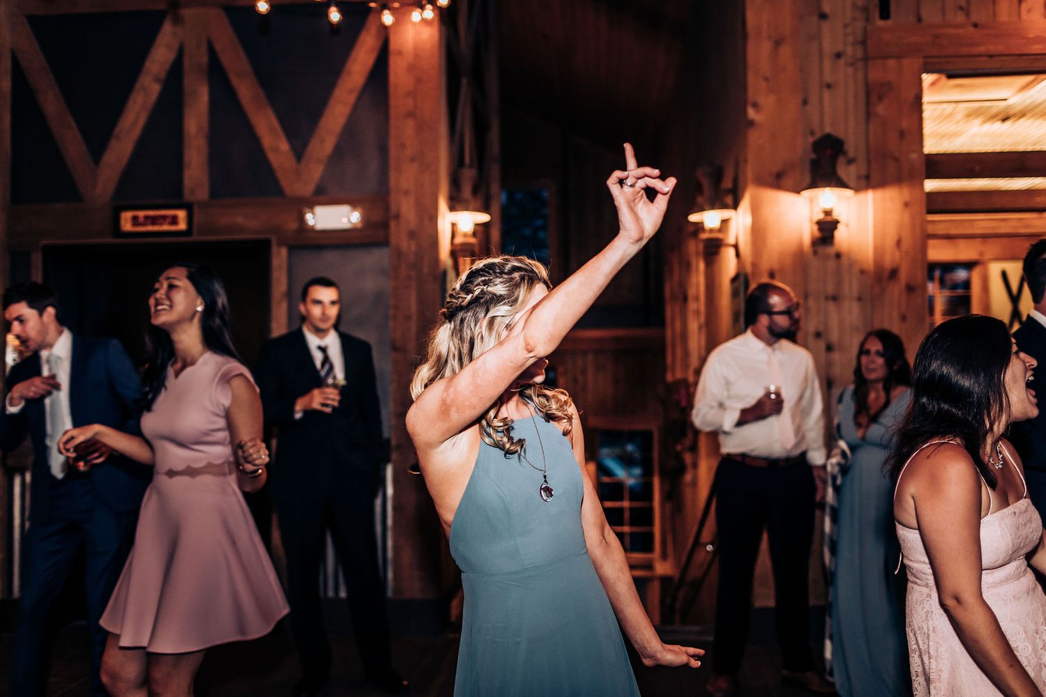 Lively dance party in rustic wooden venue with ambient lighting.