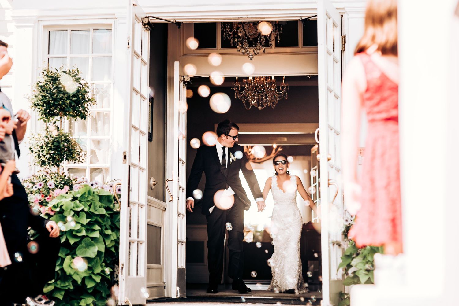 Wedding entrance through white French doors decorated with hanging lanterns and greenery.