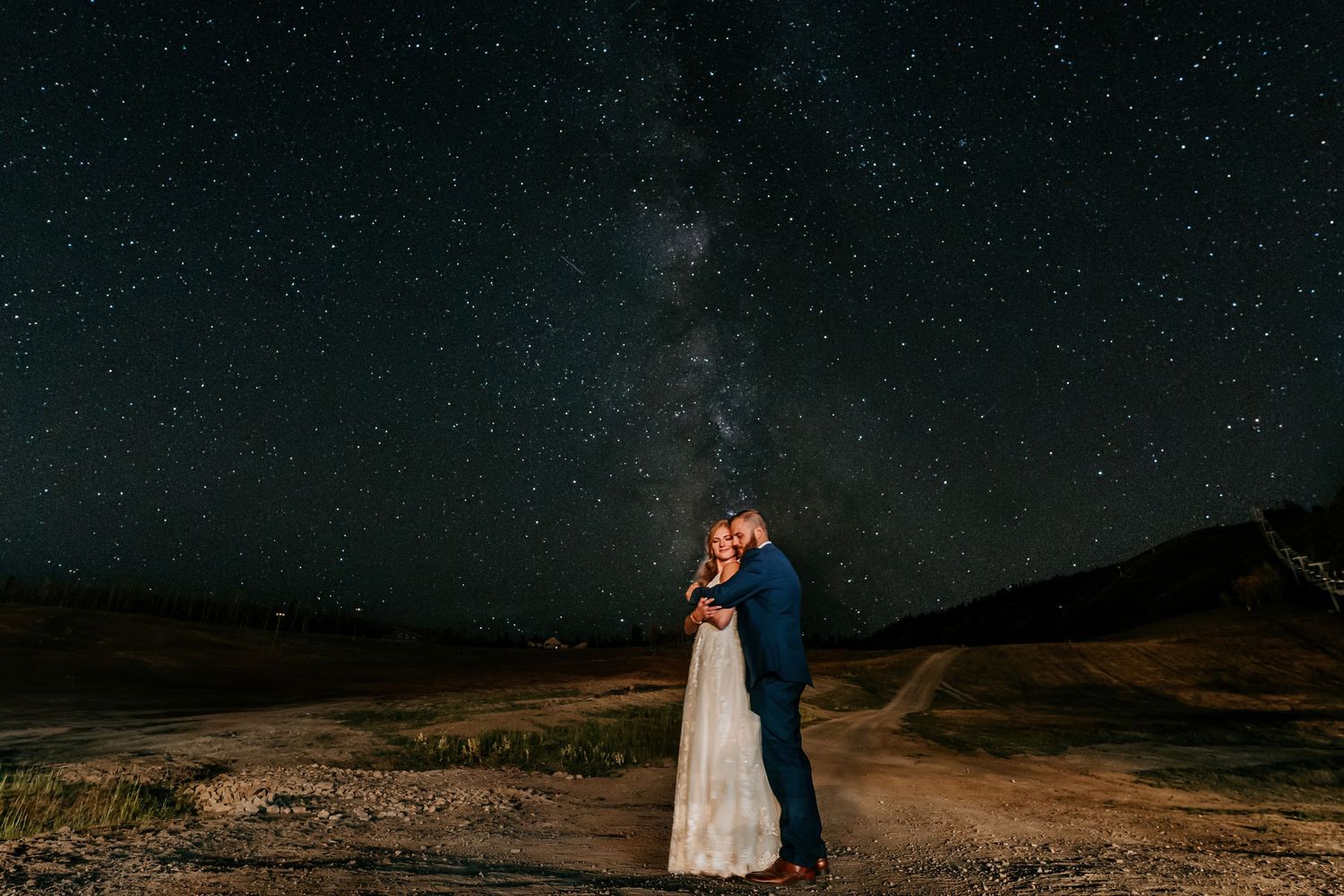 A starlit night sky creates a dramatic backdrop for a romantic mountain photoshoot.