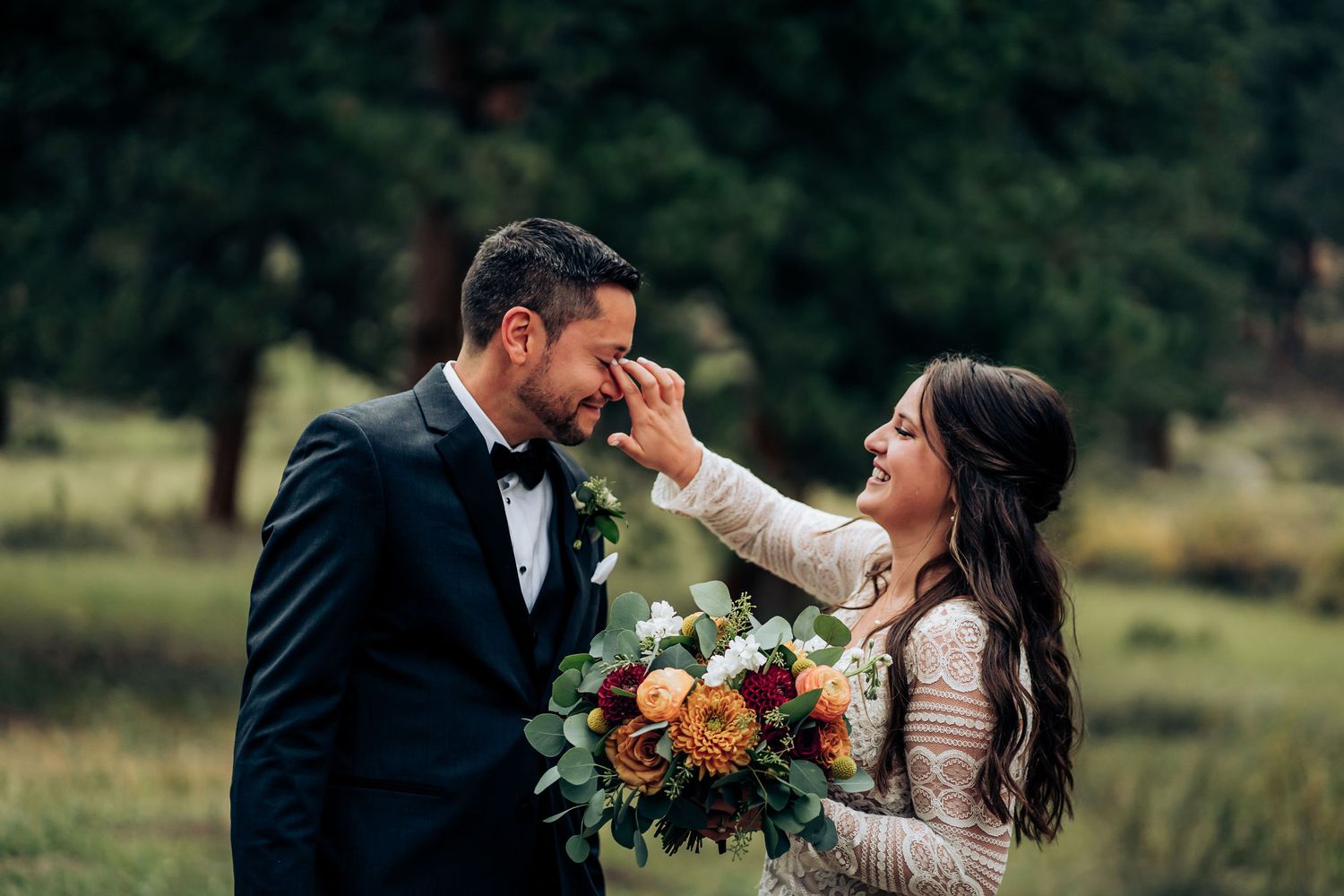 Touching wedding moment shared in mountain forest with autumn bouquet.