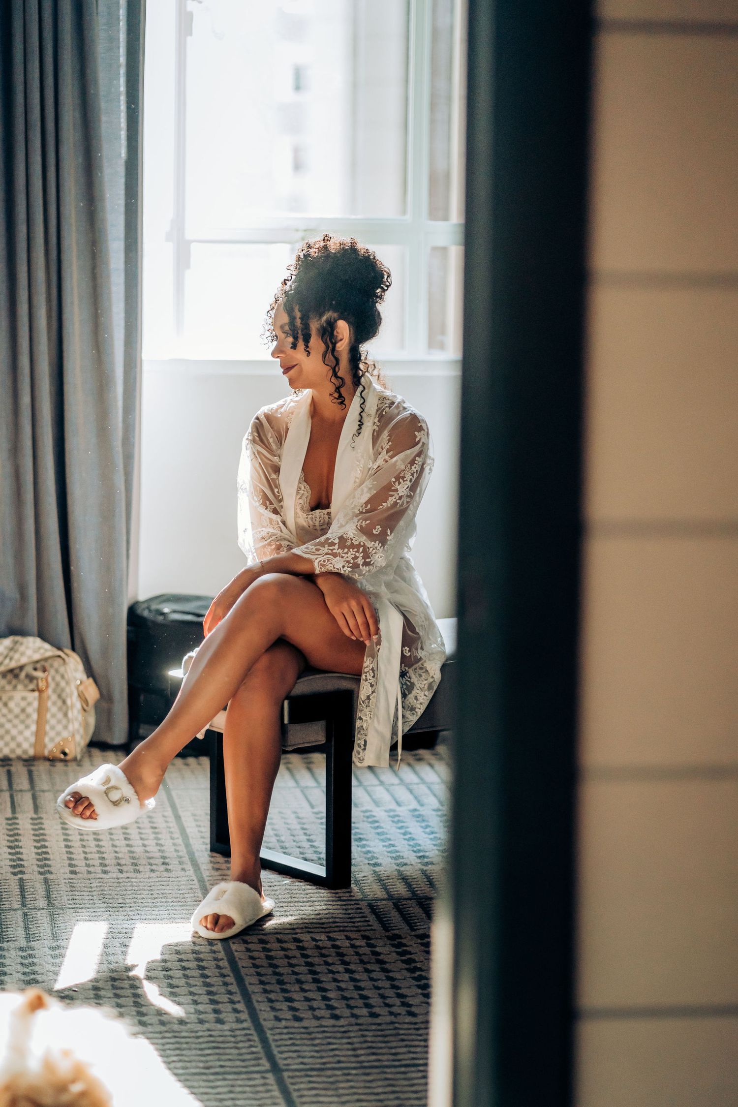 Candid portrait of someone in a lace robe sitting by a window.