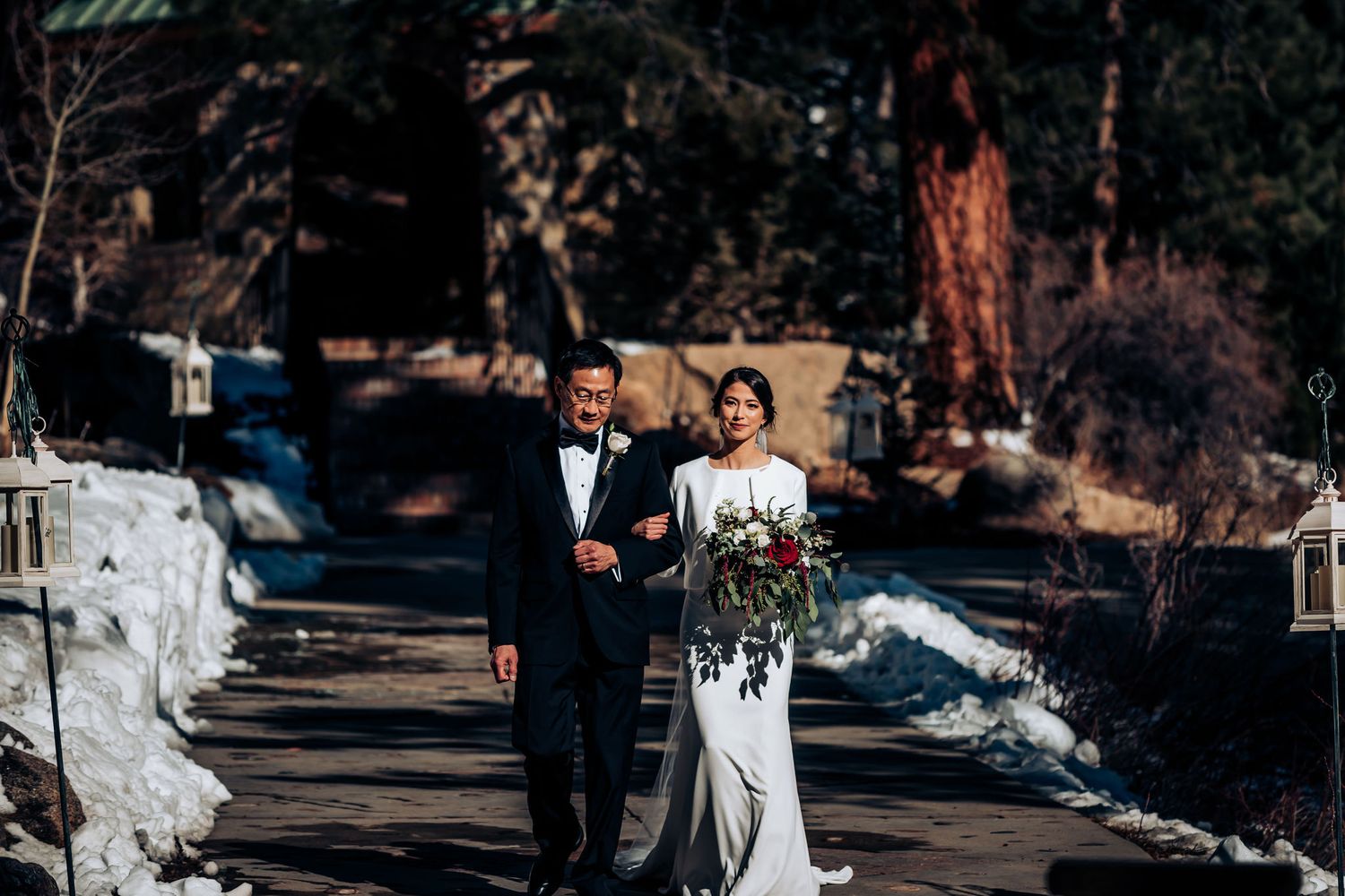 Traditional wedding processional on snowy mountain path with father escorting bride.