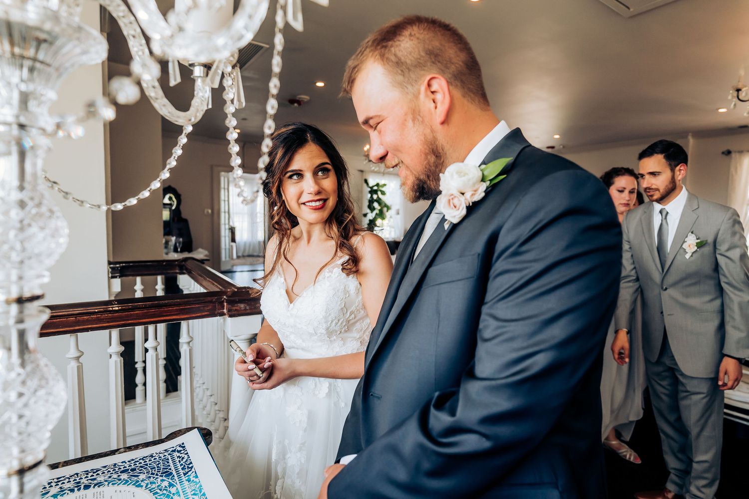 Wedding ceremony moment under crystal chandelier in elegant indoor venue.