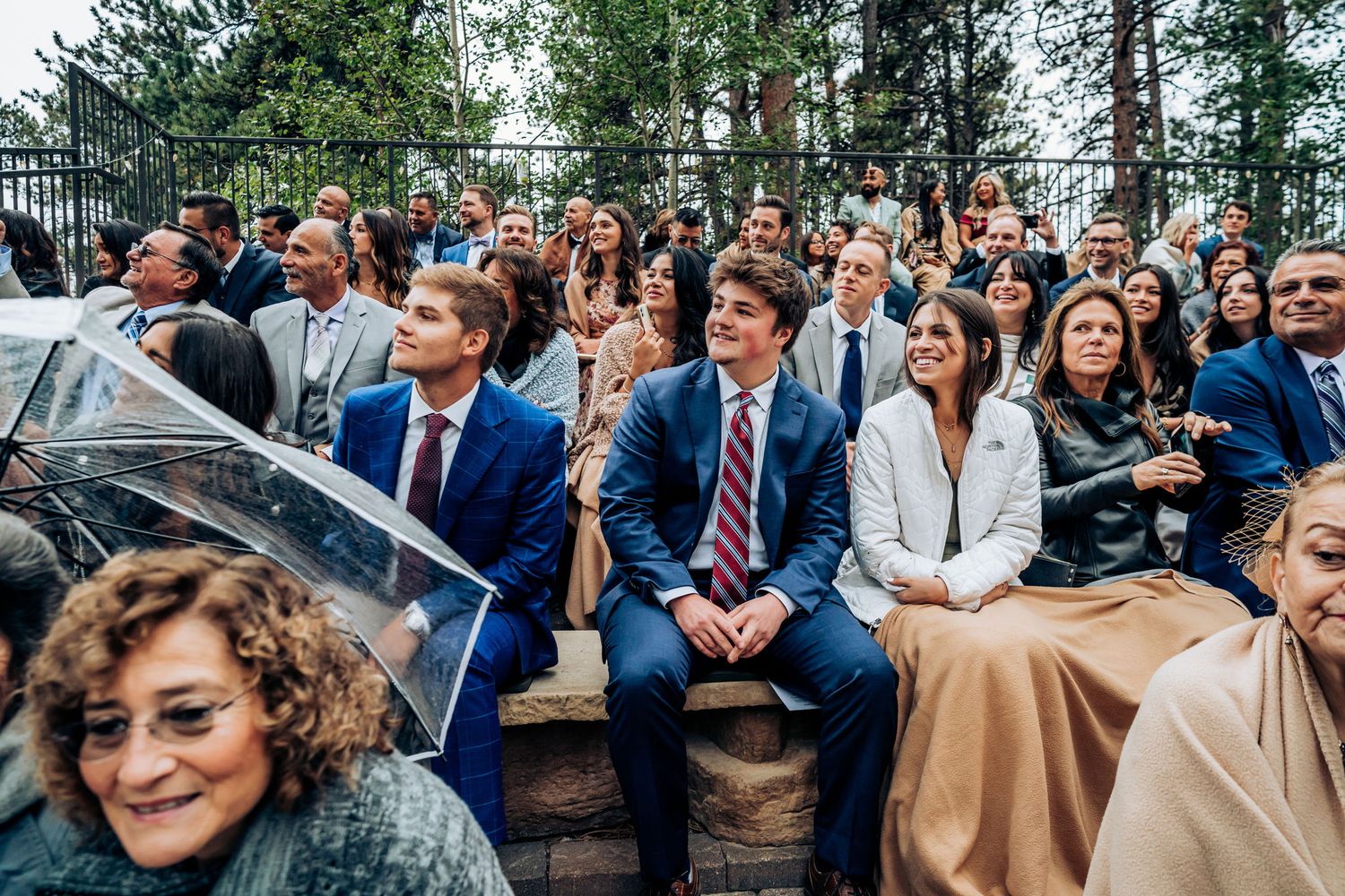 Wedding guests seated outdoors in formal attire at a mountain venue.