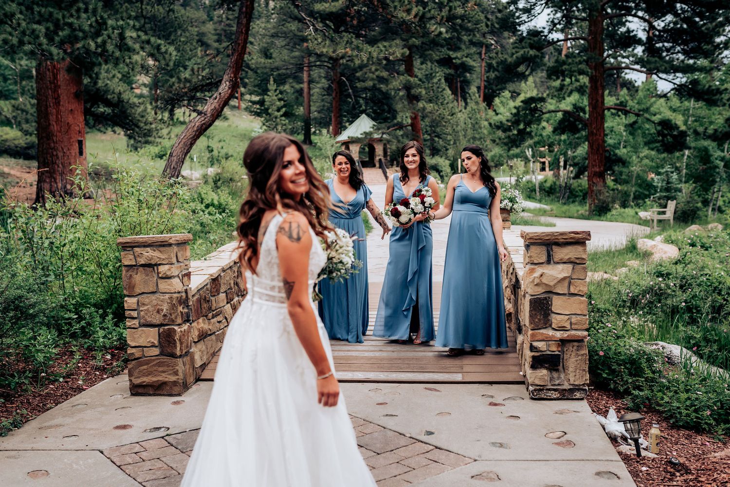 A joyful wedding scene on a stone pathway with attendants in flowing blue dresses.