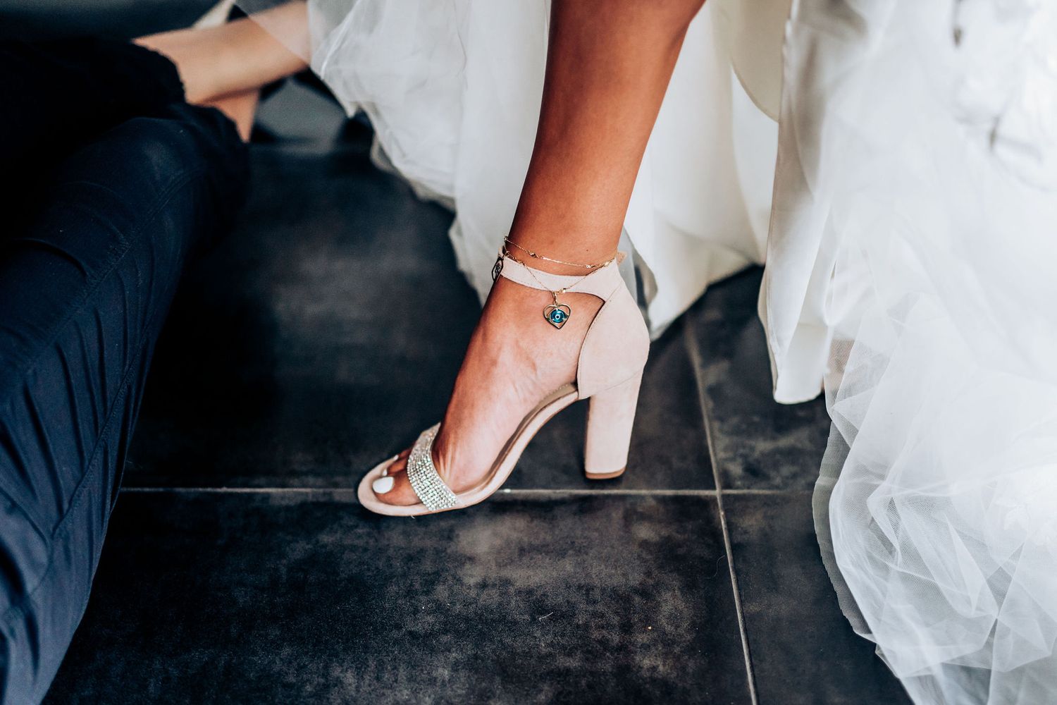 Close-up shot of an elegant bridal sandal with ankle strap against dark flooring.