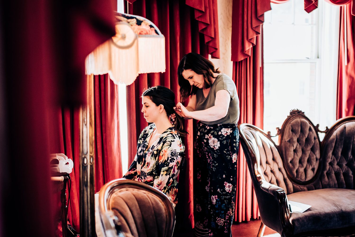 Wedding preparation scene with elegant red curtains and vintage furniture.