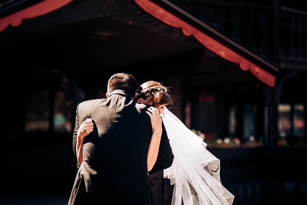 A candid moment at a wedding showing a couple from behind against a dark building backdrop.