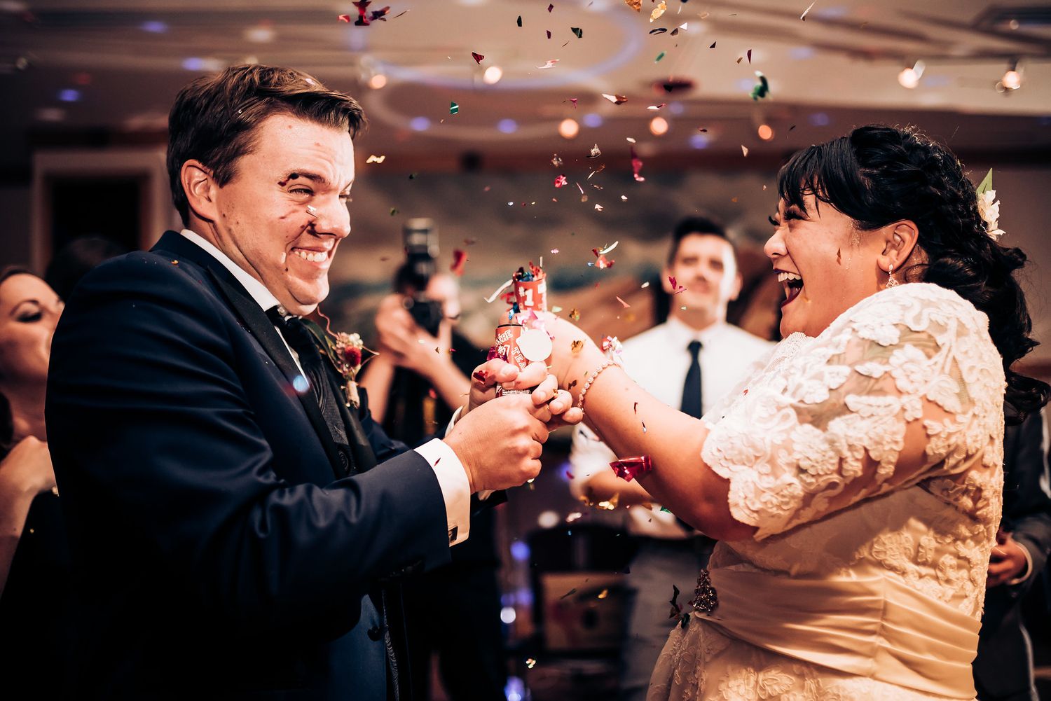 Joyful couple popping party poppers during their wedding celebration.