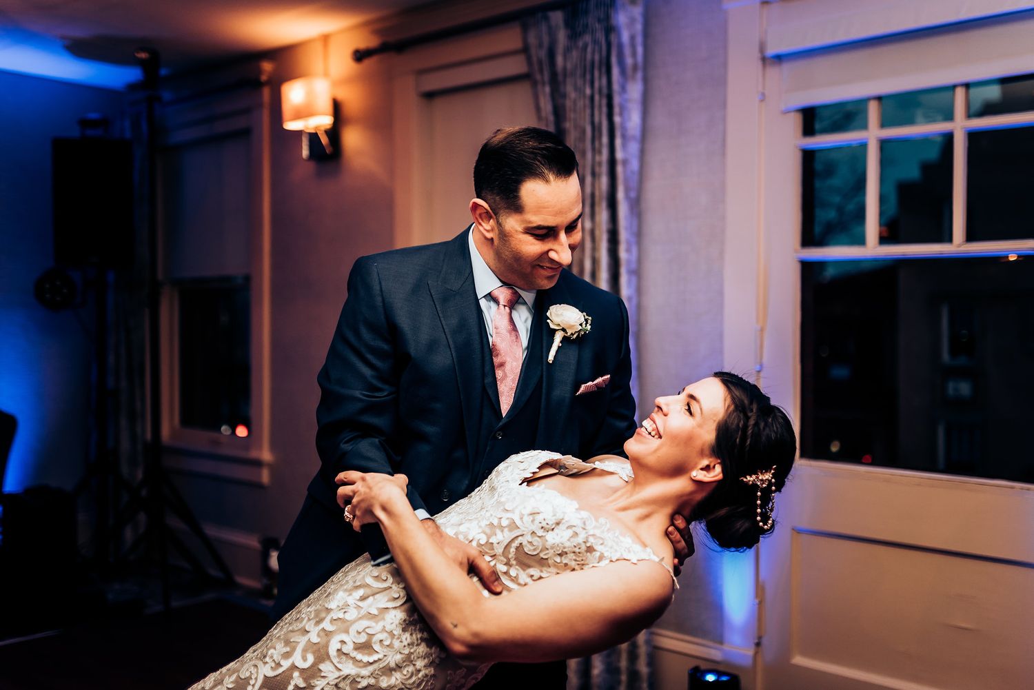 Dancing couple performs dramatic dip move under warm indoor lighting.