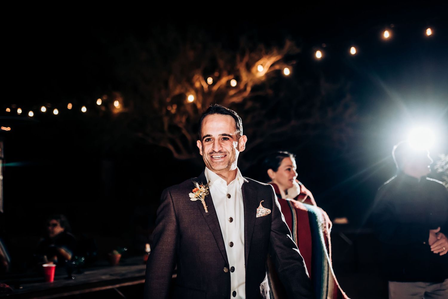 Outdoor evening celebration with string lights and professional lighting creating ambiance.