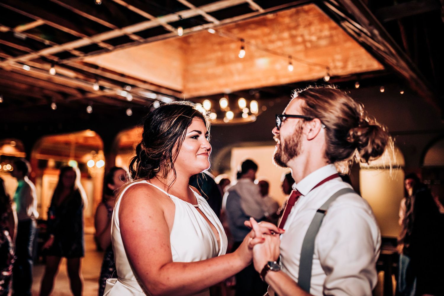 Affectionate couple dancing closely together during their wedding reception in a warmly lit venue.