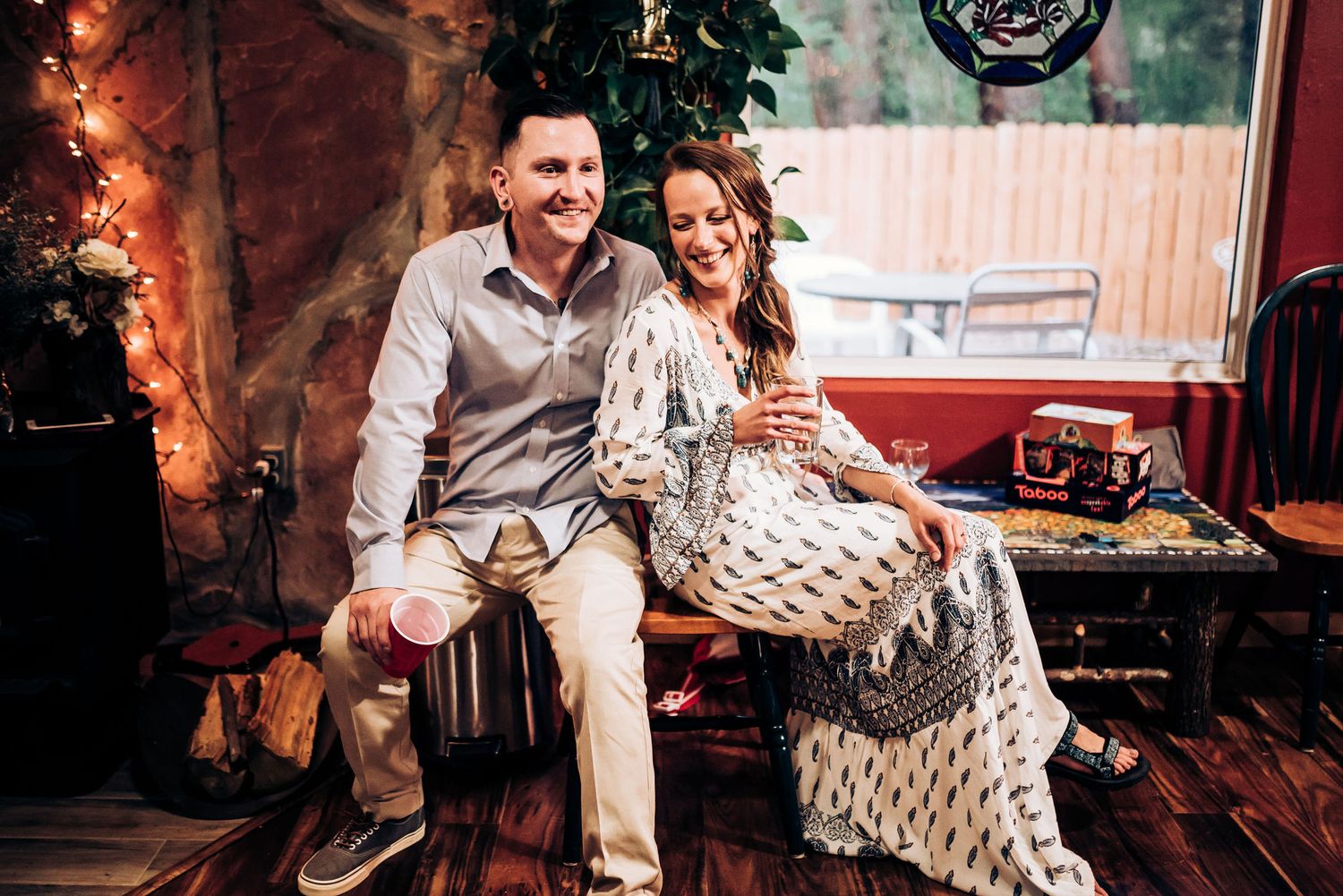 A couple enjoying a festive moment together on a decorated porch with twinkling lights.