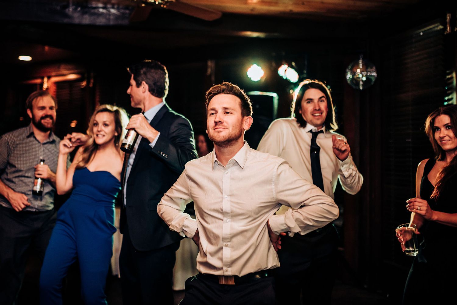 People dancing and celebrating at a lively indoor party with colorful lighting.