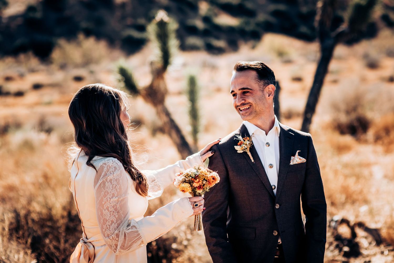 A couple shares a joyful moment during their desert wedding ceremony surrounded by cacti.