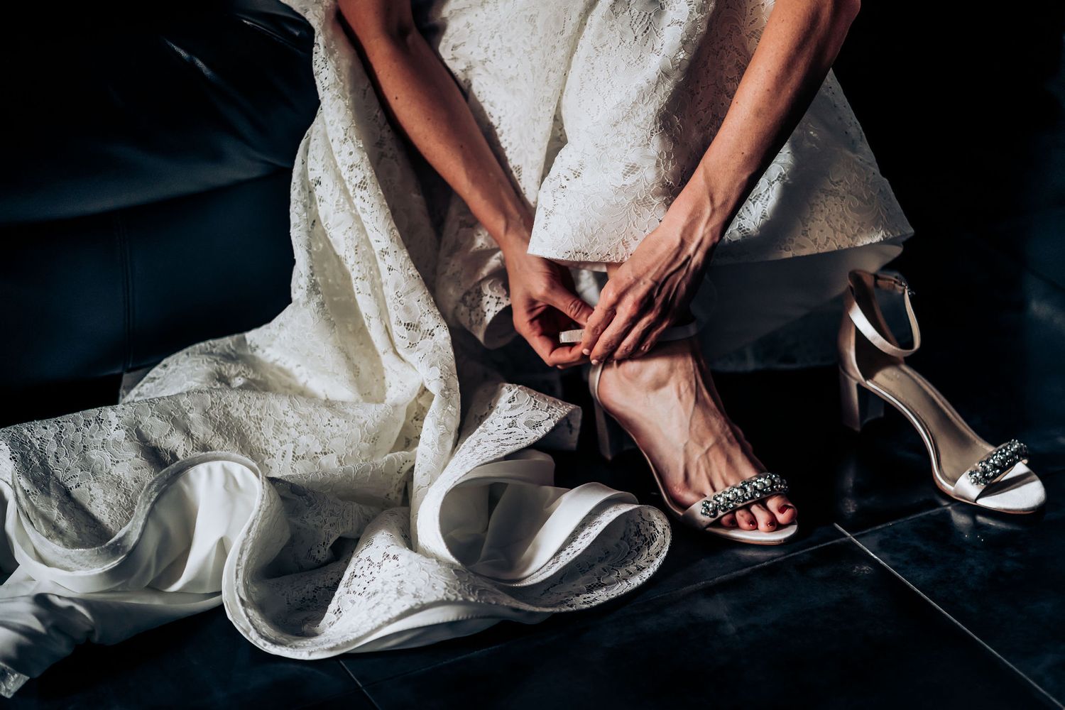 Close-up of wedding shoes being put on with flowing white dress fabric.