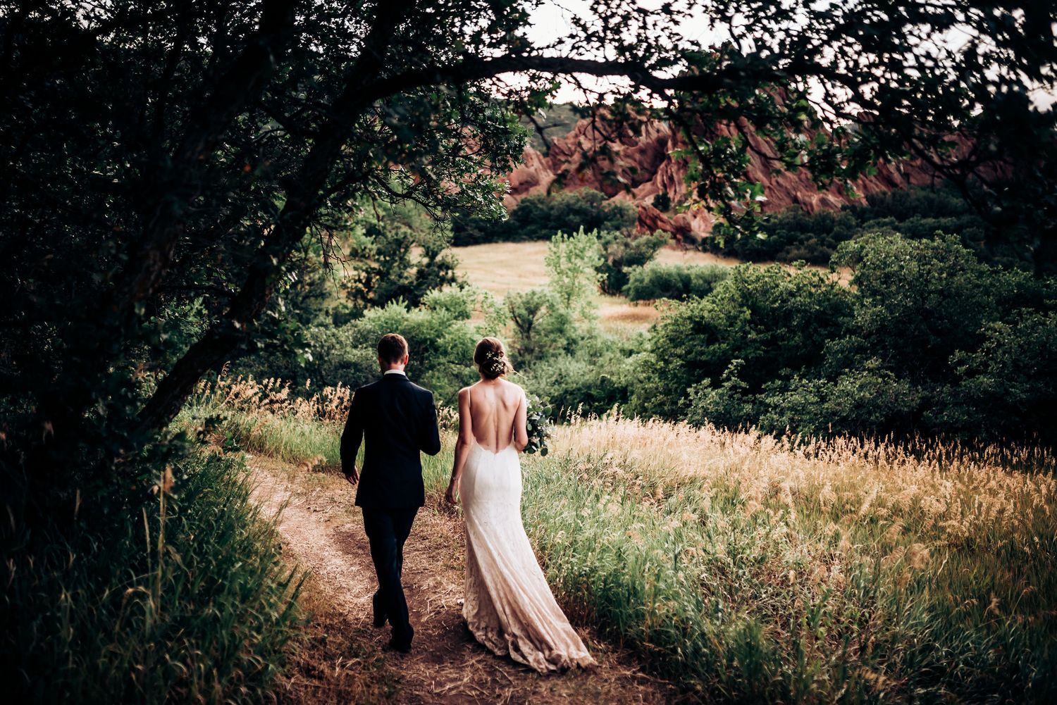 Couple strolls along winding path through serene mountain meadow.