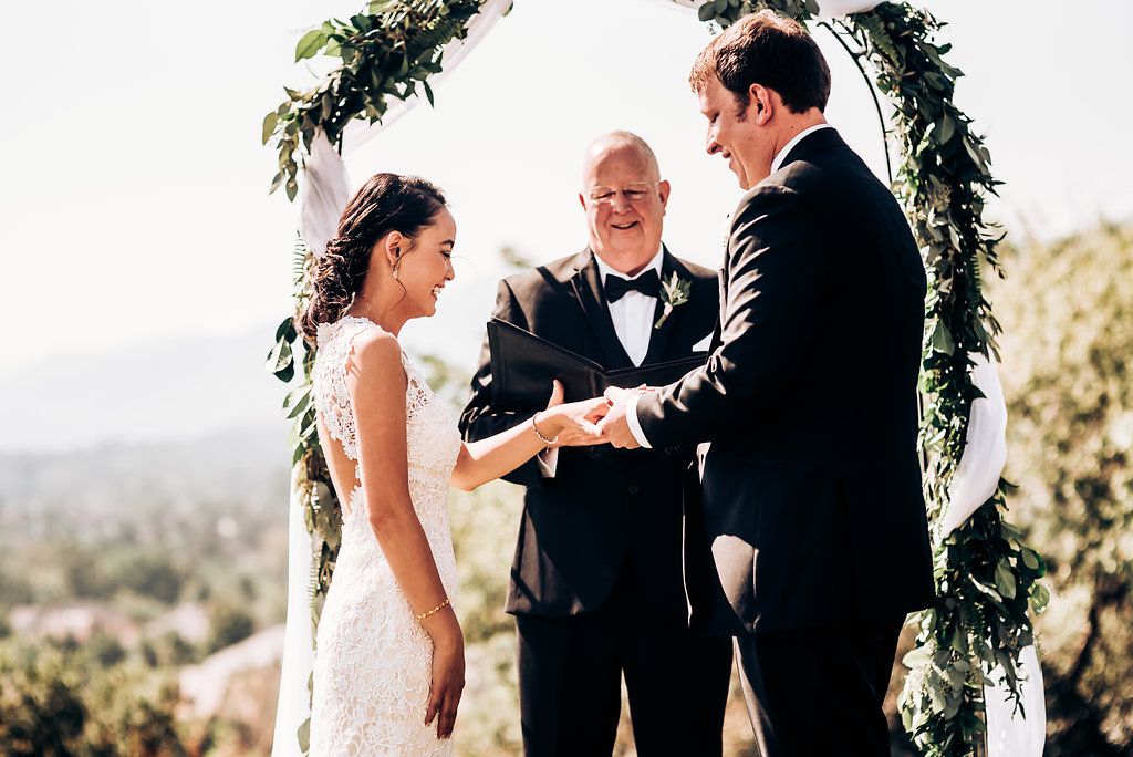 Wedding ceremony under floral arch with stunning mountain backdrop.