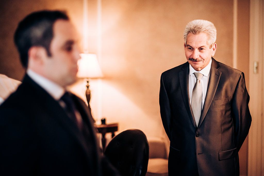 Two men in formal attire having a conversation in warm lighting.