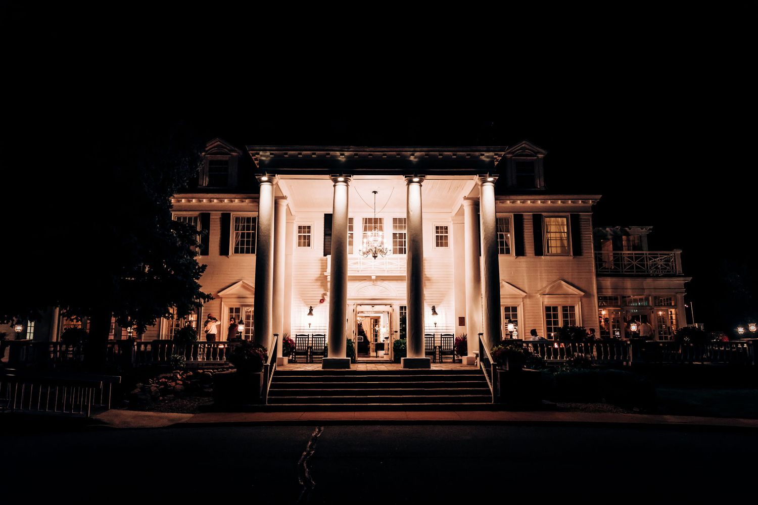 Elegant mansion venue illuminated at night with classic white columns and outdoor lighting.