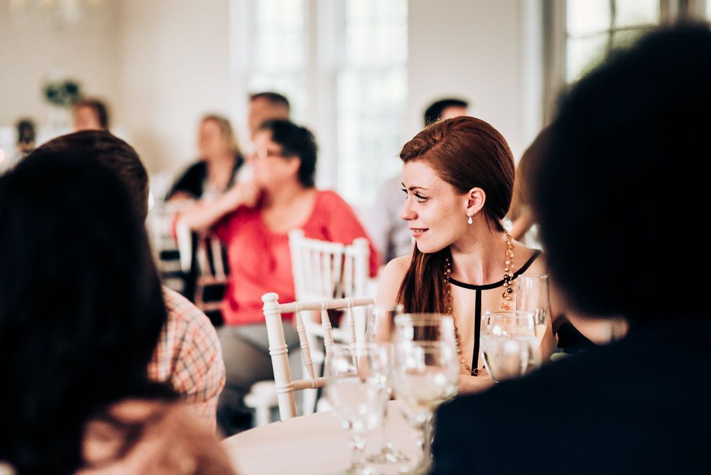 Reception guests engaged in conversation around elegant table settings at a wedding celebration.