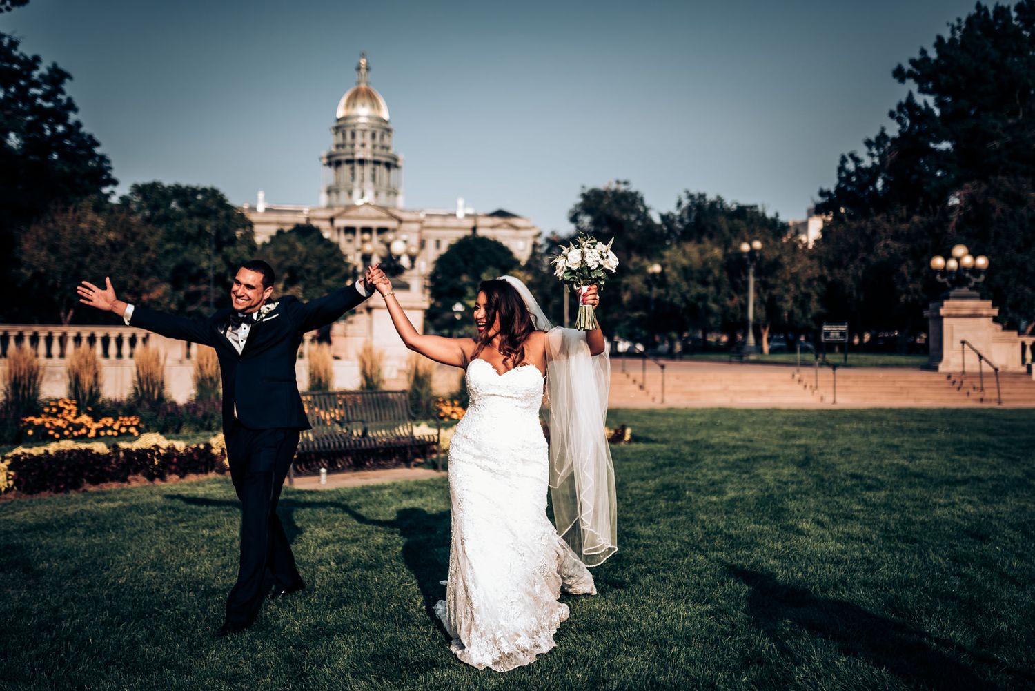 A couple celebrates their wedding day with a dance on the lawn in front of a historic building.