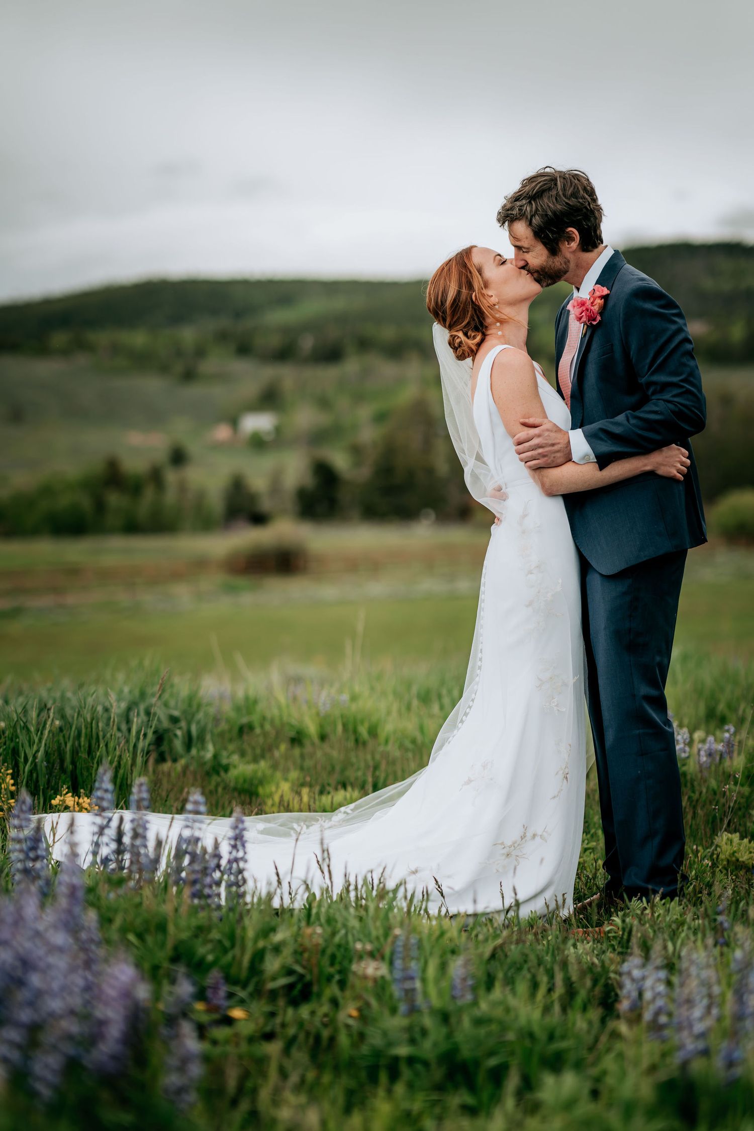 A romantic wedding moment captured in a mountain meadow with blooming wildflowers.