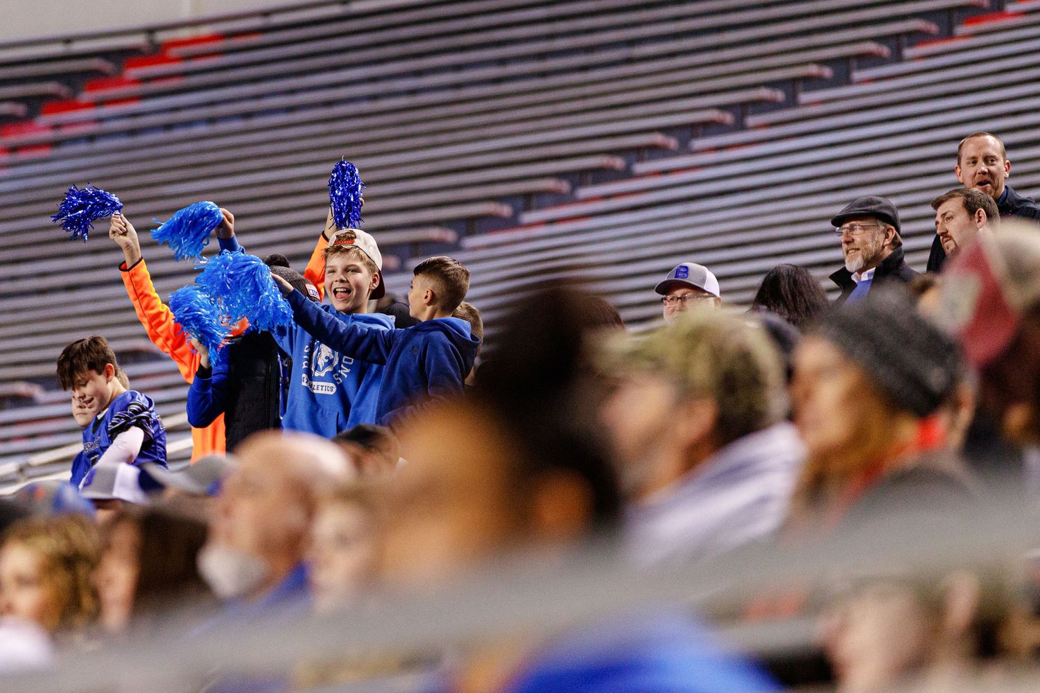 Packed stadium bleachers filled with spectators watching an intense football game.