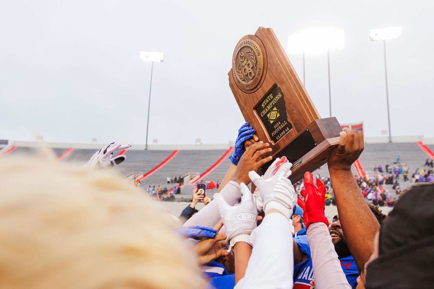 Team celebrates by hoisting championship trophy in the air.