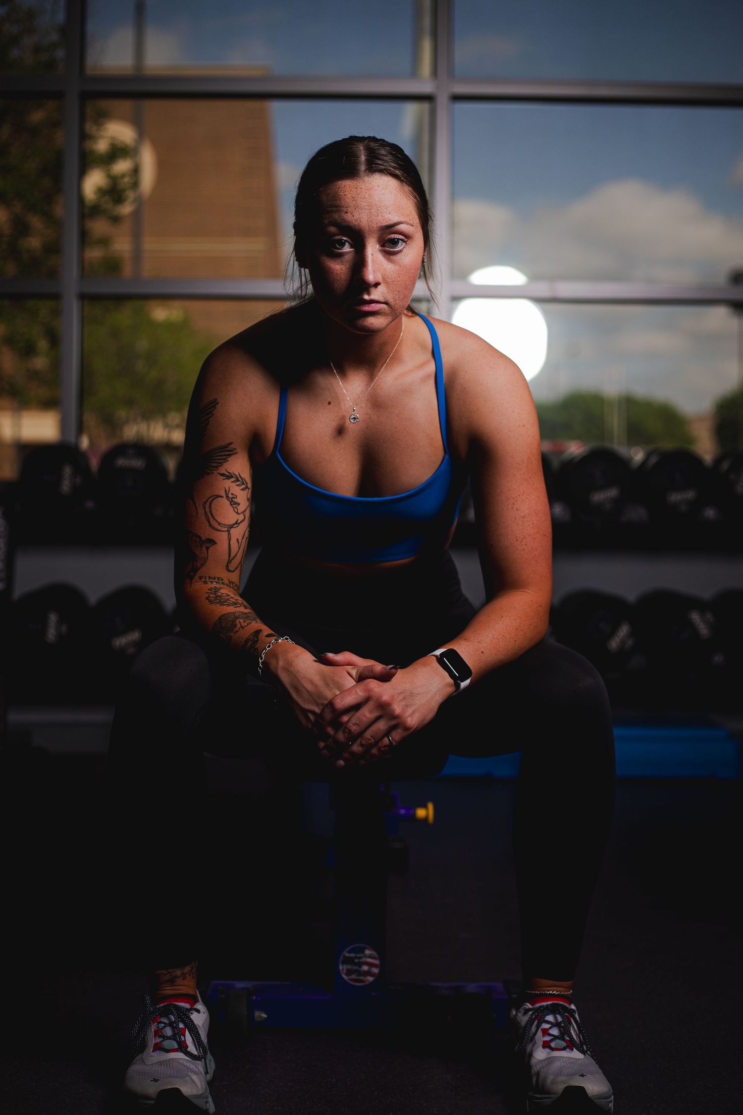 Dramatic athletic portrait series showing person in blue tank top at sunset through window.