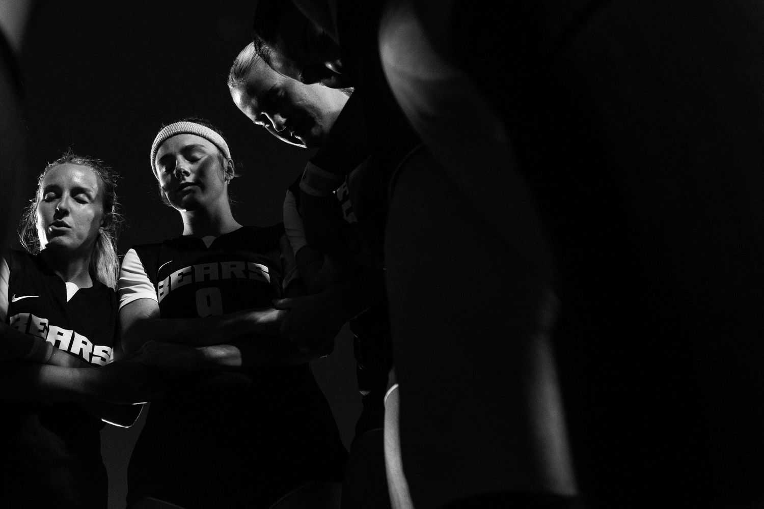 Dramatic black and white photo of performers on stage in theatrical lighting.