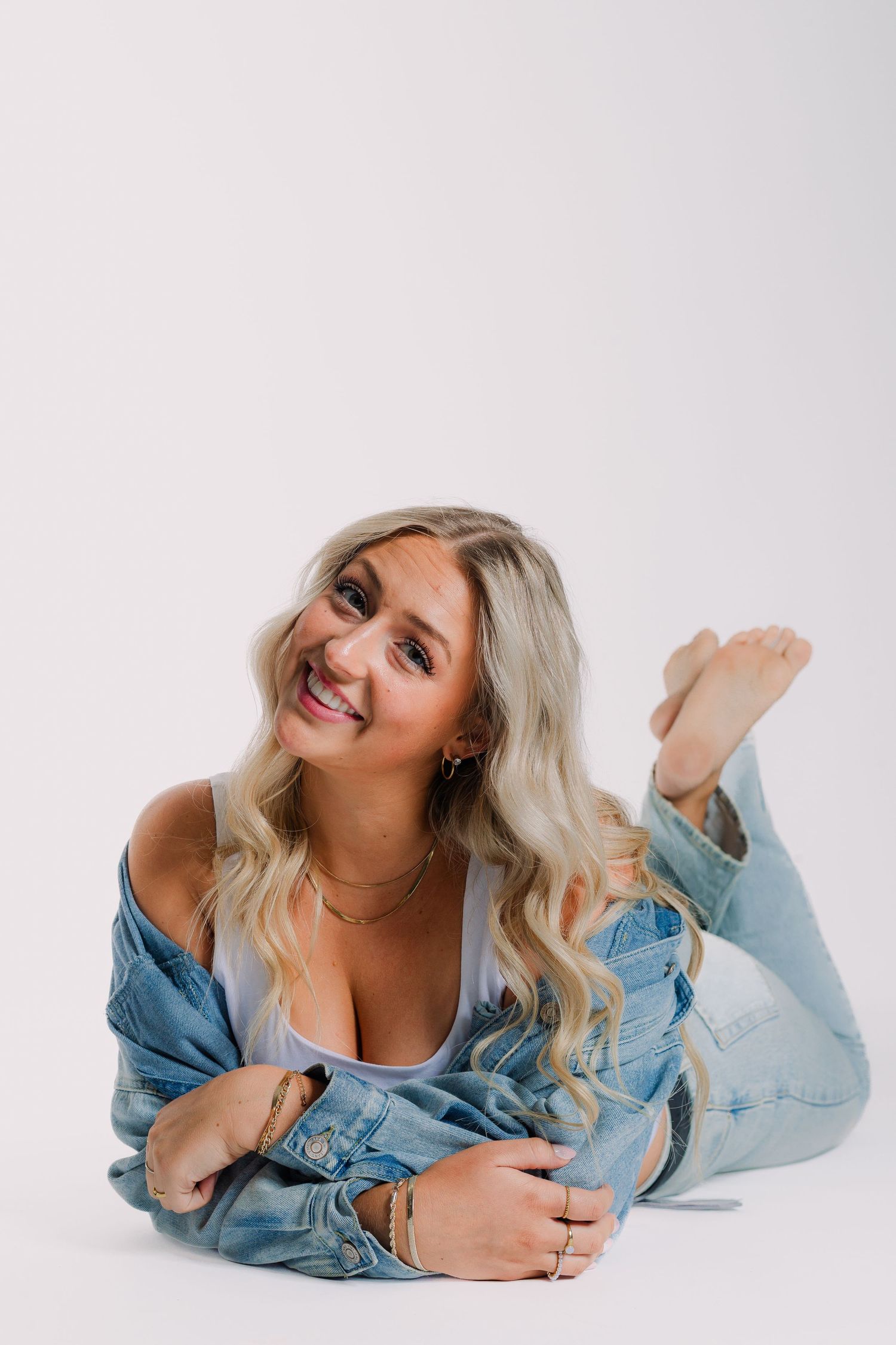 Casual lifestyle portrait of a person lying on white background wearing denim jacket and jeans.