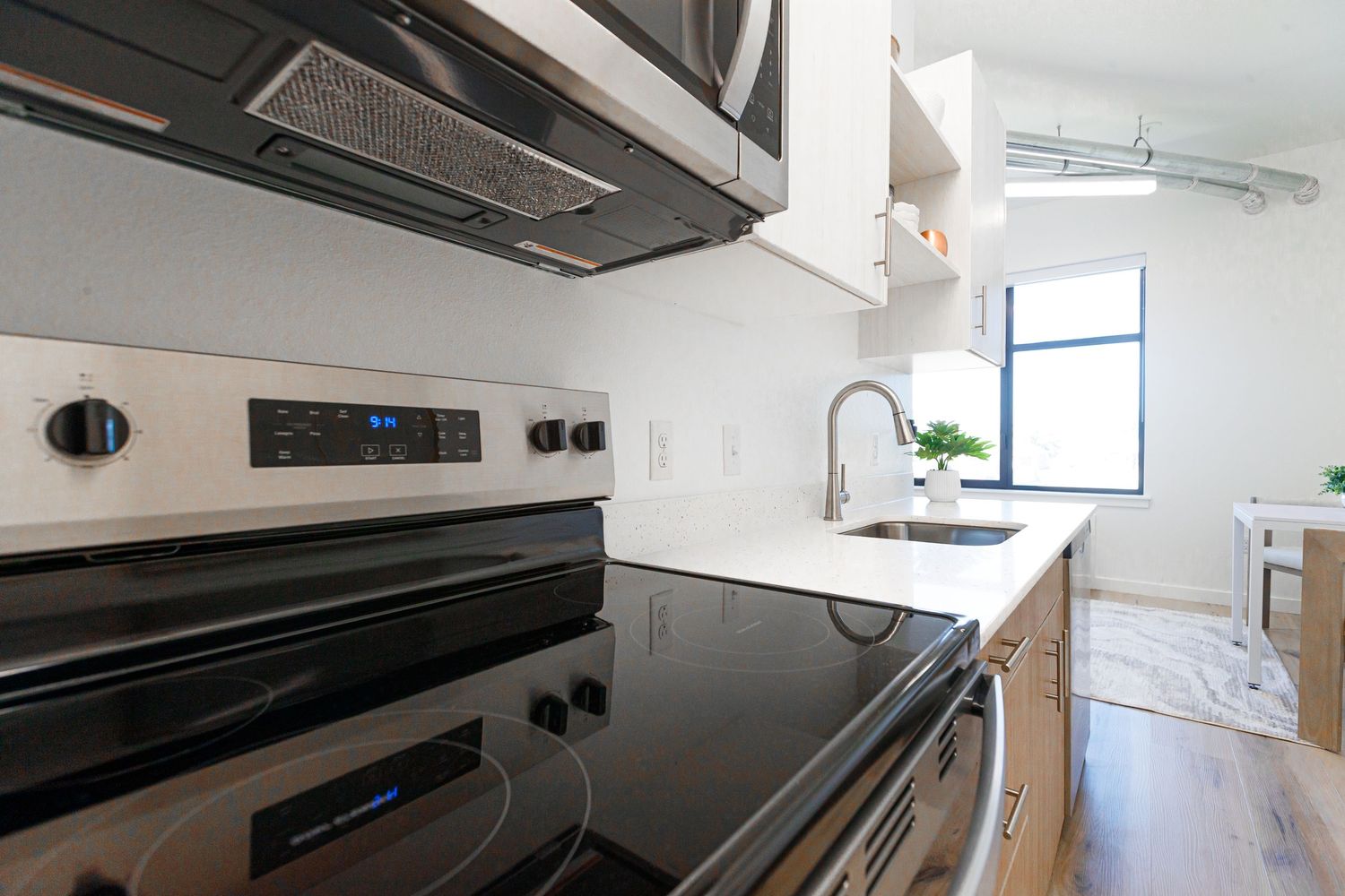 Modern kitchen with black glass cooktop, stainless range hood, and white cabinets.