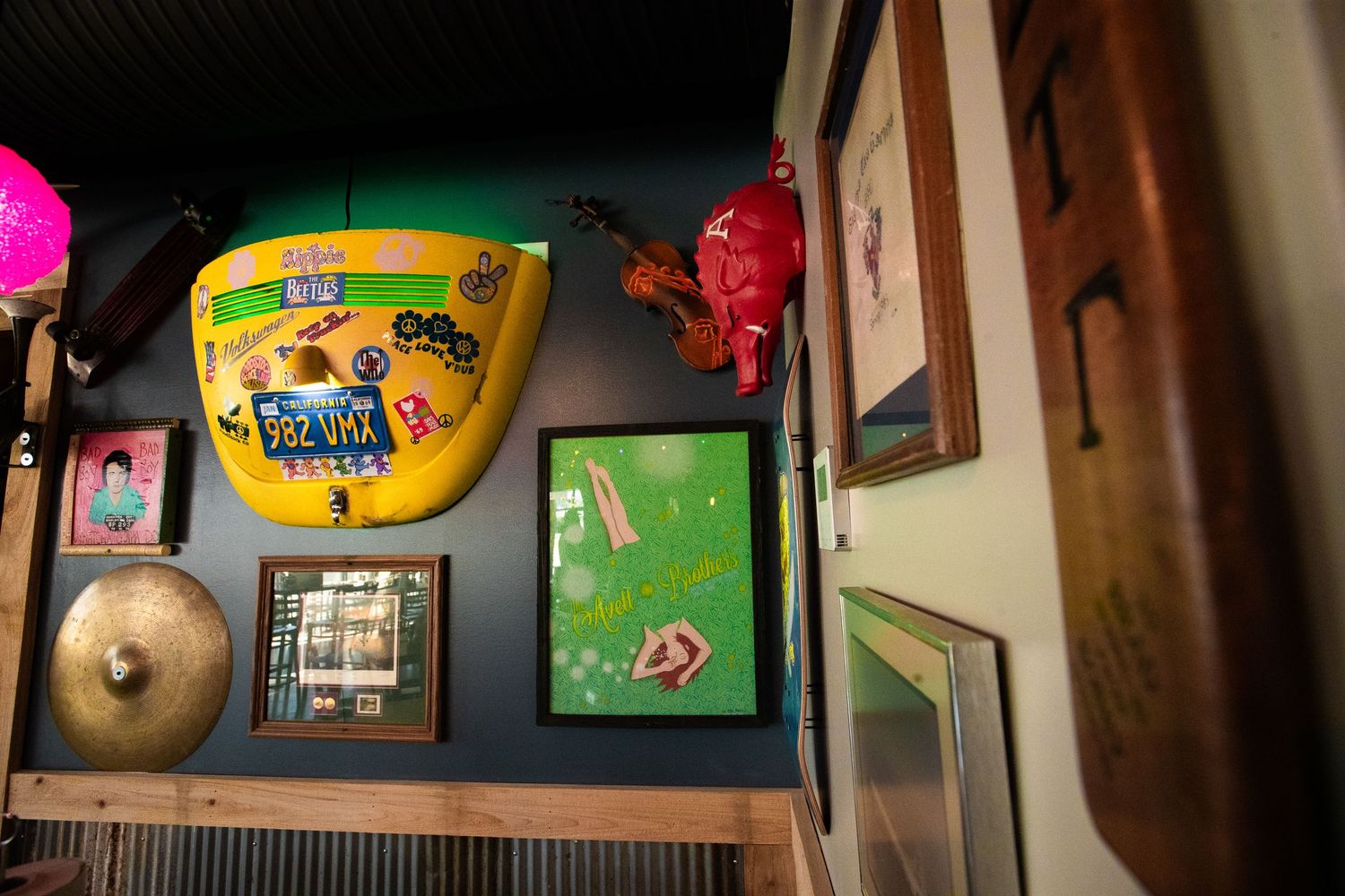 Eclectic wall display featuring yellow surfboard, cymbals and framed artwork.