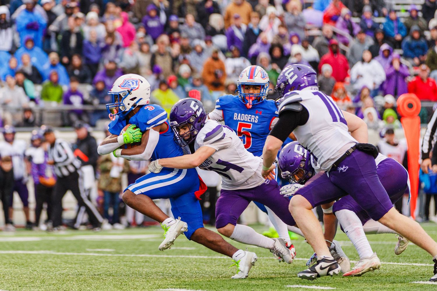 Football players from opposing teams clash during intense gameplay moment.