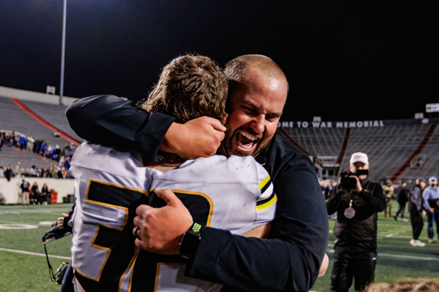 An emotional moment between players and coach during a nighttime football game.