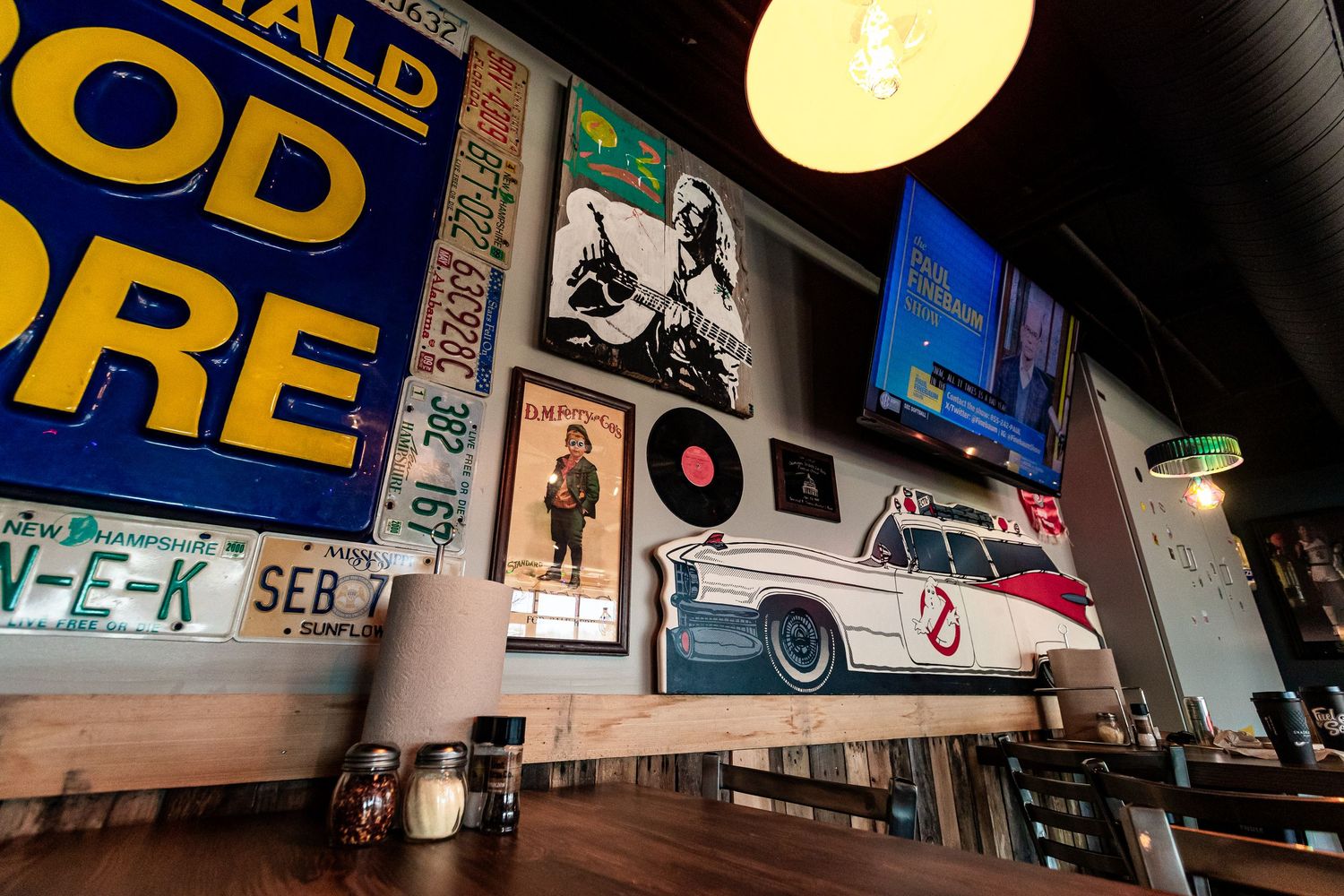 Restaurant wall decorated with retro posters, vinyl records and vintage car artwork.