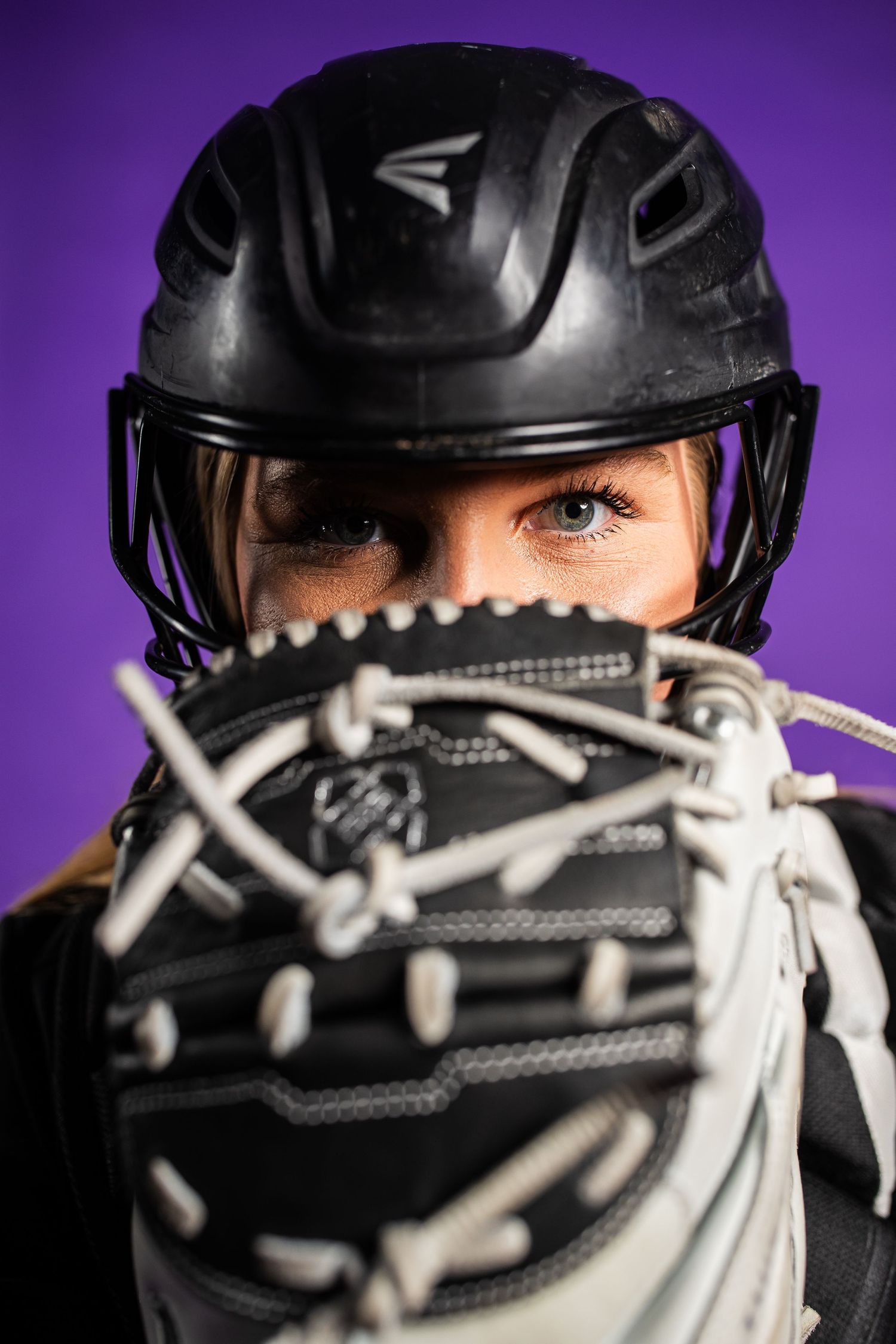 Close-up series of intense eyes behind a sports mask with white laces against a purple backdrop.