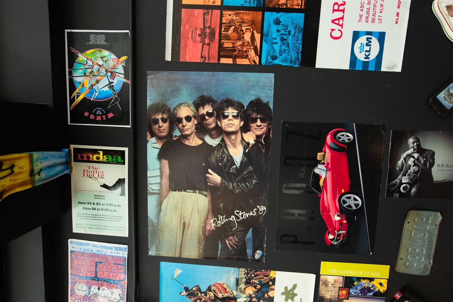 Vintage memorabilia collection displayed on dark wall including photographs and decorative items.