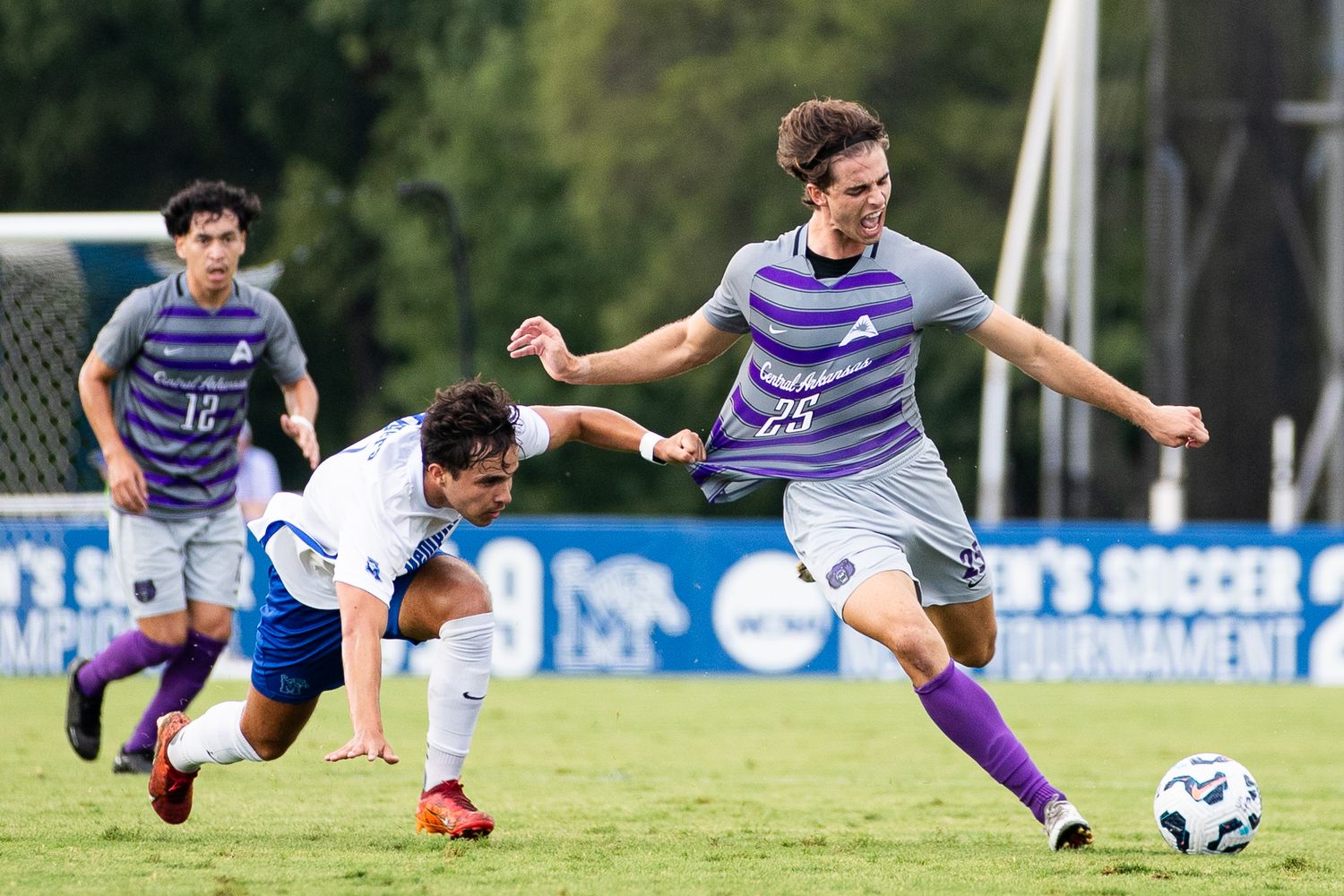 Soccer players in striped uniforms slide and dive for the ball during an intense match.