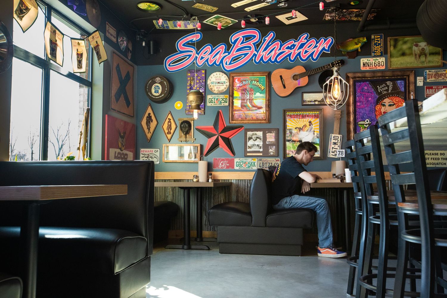 Retro-style restaurant interior with Sea Blaster neon sign and vintage decorations on walls.