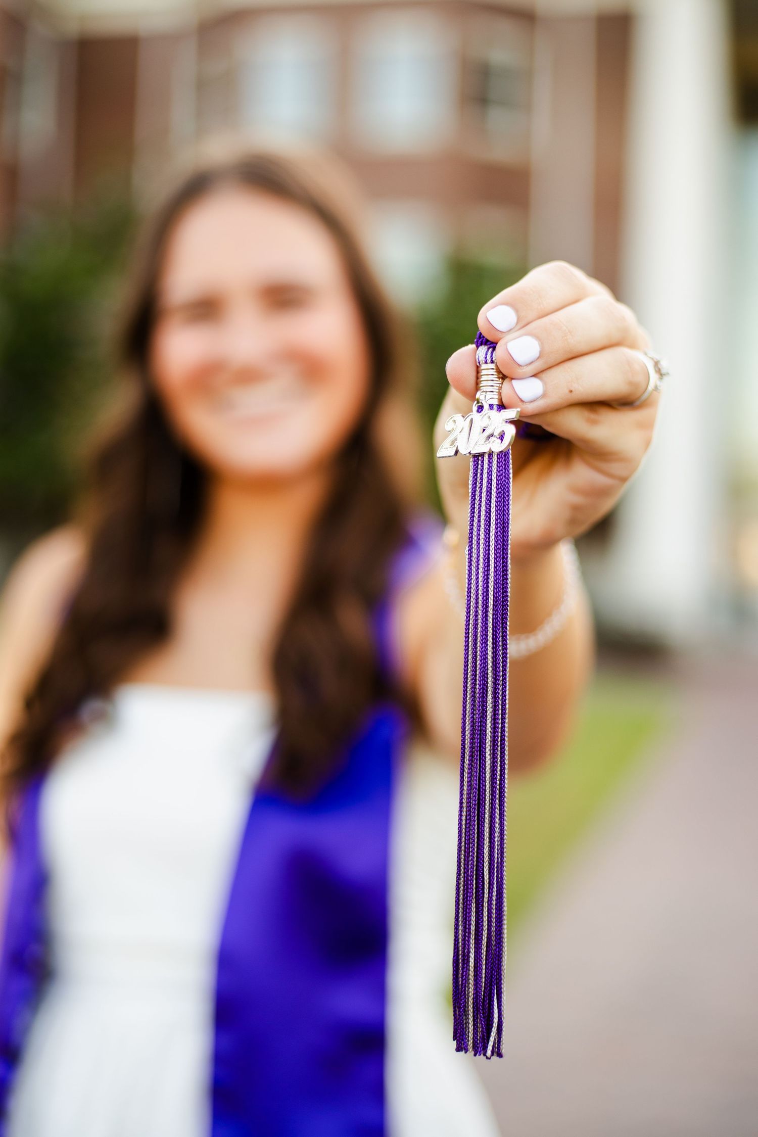 Person in blue dress holds purple graduation tassel against blurred brick backdrop in progression of shots.