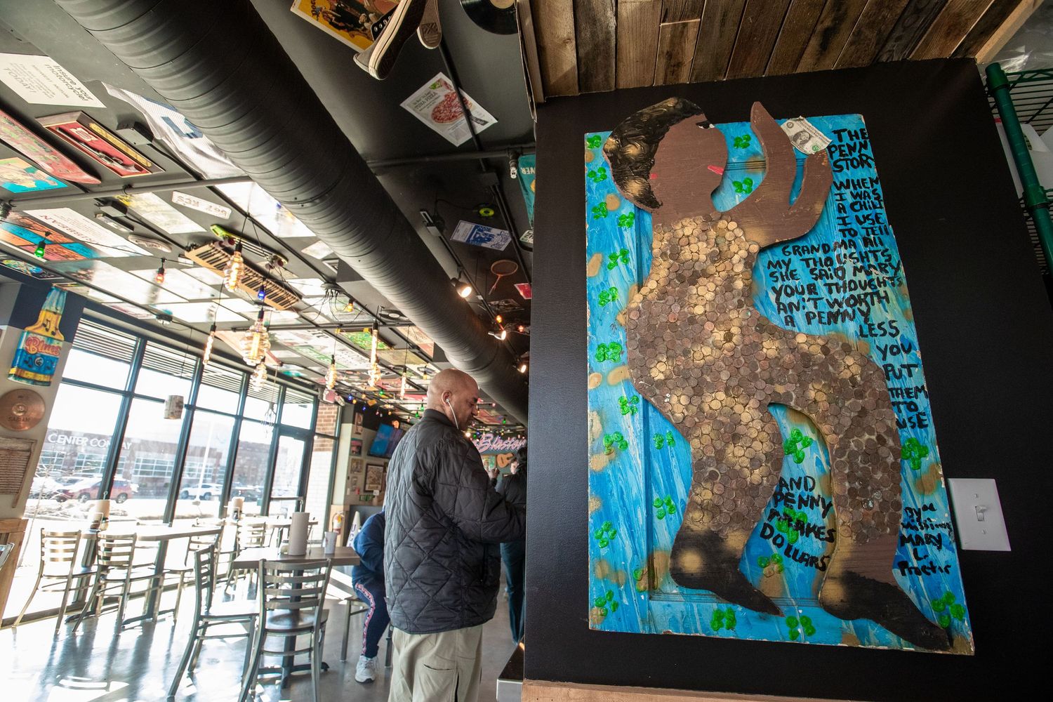 Modern restaurant interior with artistic wall decor and hanging pendant lights.