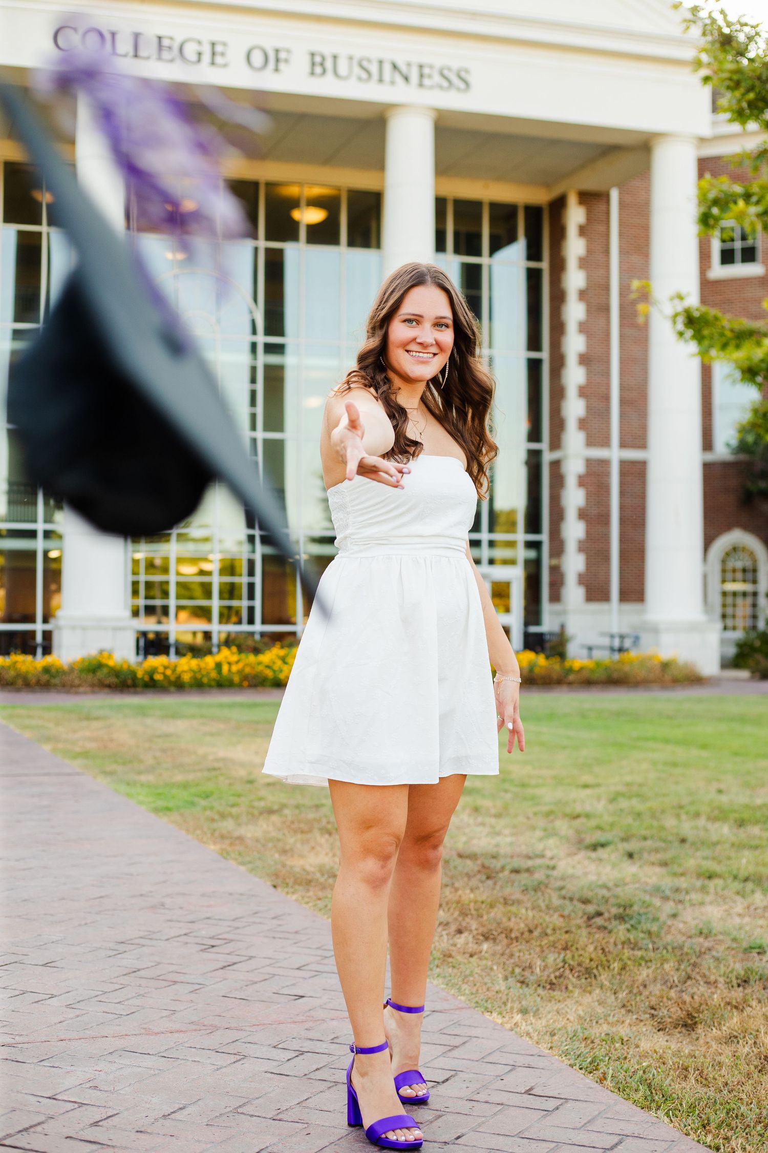 Professional photo session showing purple stilettos and graduation cap toss at university business college campus.