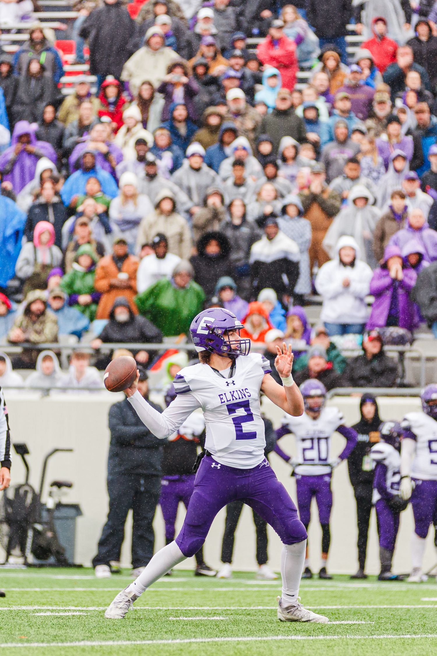 Quarterback in purple uniform prepares to throw pass during game.