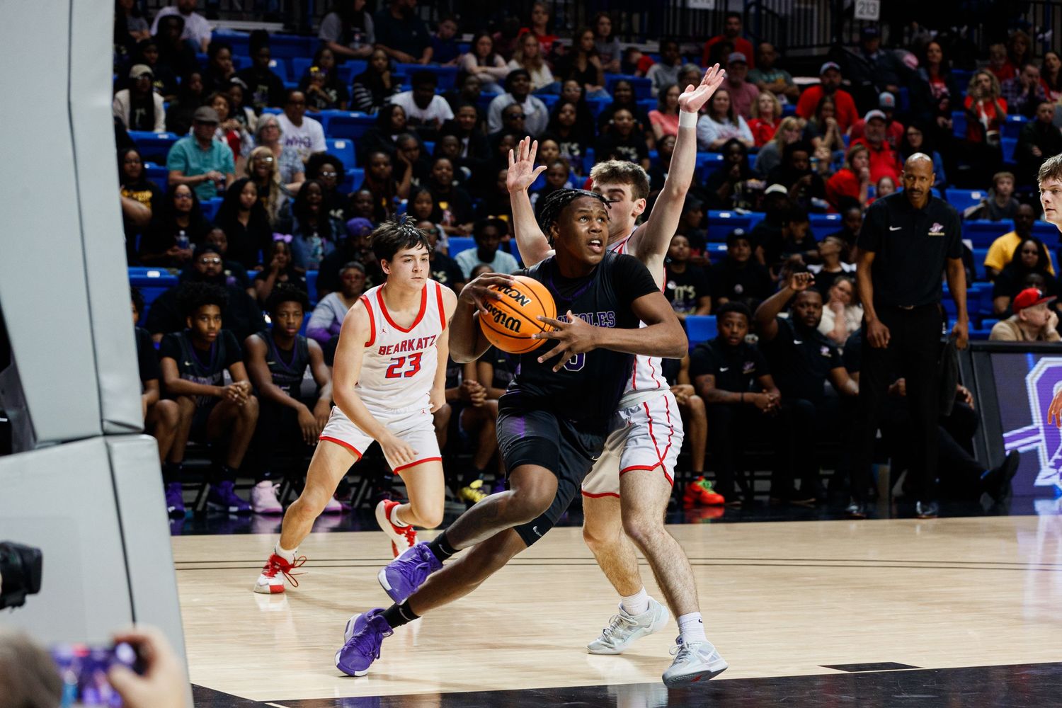 Basketball players from opposing teams battling for position during game.